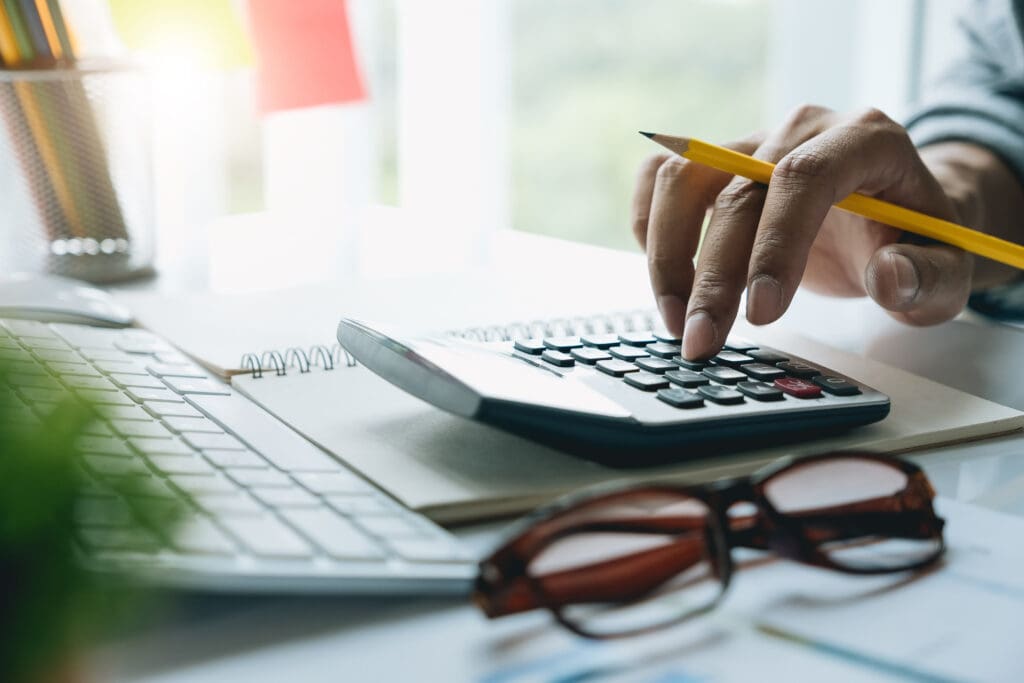 Person berechnet an einem Taschenrechner die Kosten für einen 1 MWh Batteriespeicher