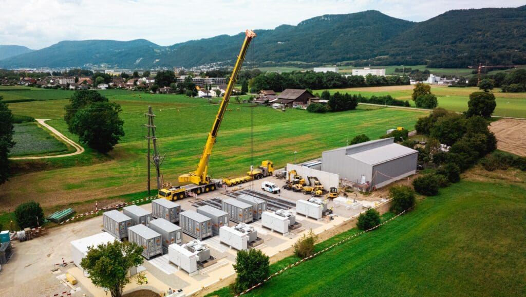 Draufsicht Anlieferung des 65 MWh-Batteriespeichers in Kappel aus der Vogelperspektive vor Schweizer Bergen